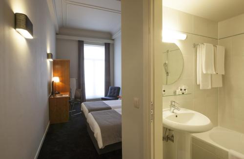a bathroom with a sink and a bed and a tub at Theater Hotel Leuven Centrum in Leuven