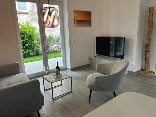 a living room with two chairs and a flat screen tv at Timmendorfer Herz in Timmendorfer Strand