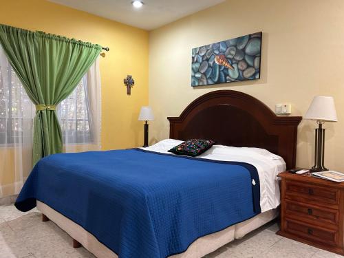 a bedroom with a bed with a blue blanket and a window at Casa Belisario - Pet Friendly in Mazatlán