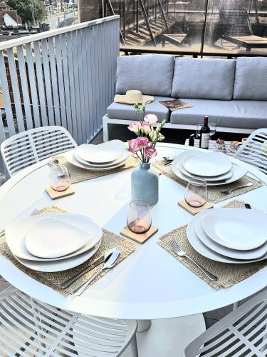 a white table with plates and a vase of flowers at Cozy Rooftop - Sint-Idesbald in Koksijde