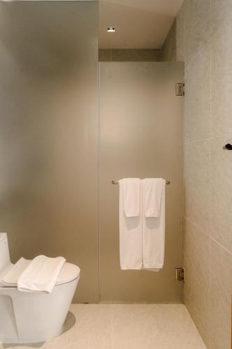 a bathroom with a shower and a toilet and towels at Richmann Resort Hotel Hatyai in Hat Yai