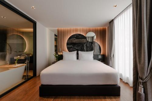 a bedroom with a large white bed and a bathroom at Richmann Resort Hotel Hatyai in Hat Yai