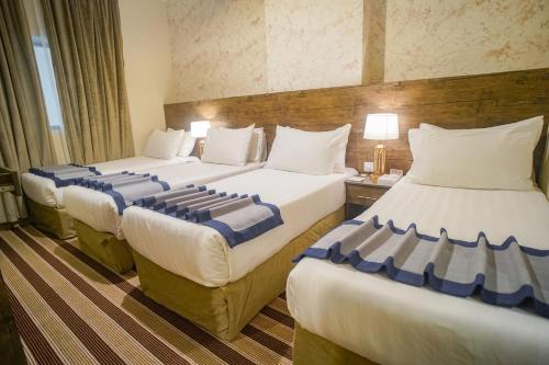 a hotel room with three beds with blue and white pillows at Emaar Al Khalil in Makkah