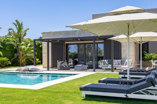 a pool with chairs and umbrellas in a yard at Iniada Villas in Chania Town