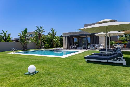 a swimming pool with two lounge chairs and an umbrella at Iniada Villas in Chania Town