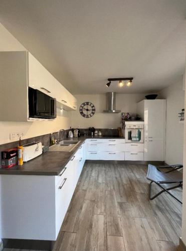 une cuisine avec des armoires blanches et un plancher en bois dans l'établissement Astrella, à Bandol