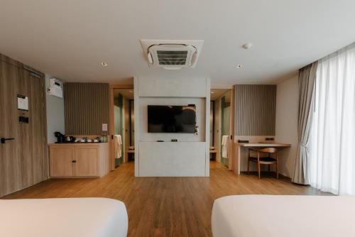 a living room with a couch and a tv and a table at Richmann Resort Hotel Hatyai in Hat Yai
