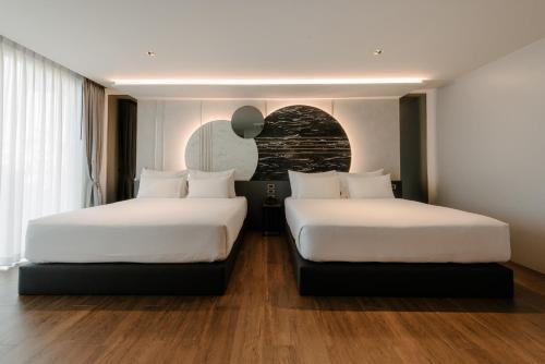 two beds in a hotel room with white sheets at Richmann Resort Hotel Hatyai in Hat Yai