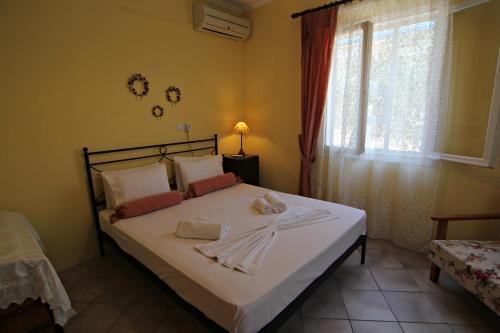 een slaapkamer met een bed met witte lakens en een raam bij Joanna's House in Skala Kallirakhis