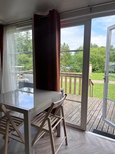 a dining room with a table and chairs on a deck at Camping du Château Vert in Hondainville