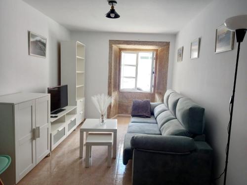 un salon avec un canapé bleu et une télévision dans l'établissement Carmen House - Laxe - Costa da Morte, à Laxe