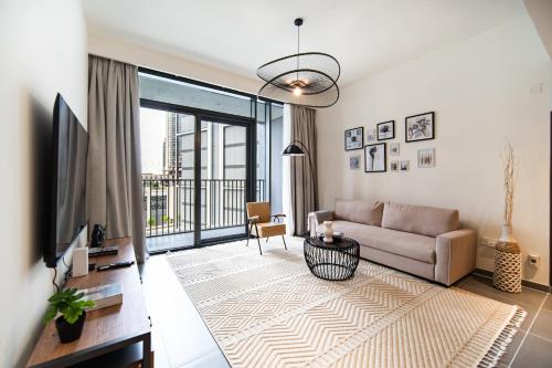 a living room with a couch and a television at SettlerHomes - Chic Creek Edge 1BR With Harbour View in Dubai