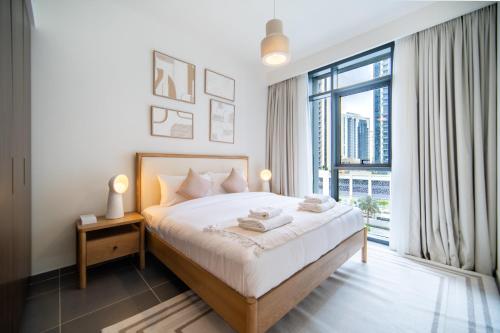 a bedroom with a bed and a large window at SettlerHomes - Chic Creek Edge 1BR With Harbour View in Dubai
