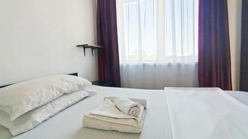 a white bed with two pillows and a window at Portofino Villa in Costinesti