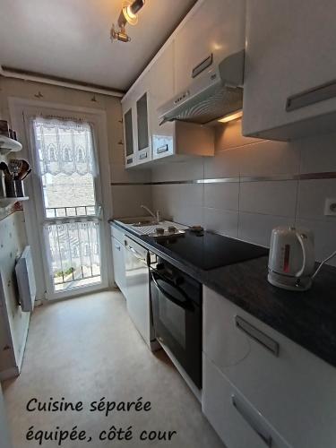 une cuisine avec des armoires blanches et un comptoir noir dans l'établissement Duplex face Mer au pied des plages exceptionnelle vue mer, à Arzon