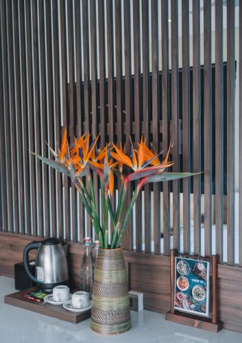 a vase with orange flowers in it on a table at Canary Dalat Hotel in Da Lat