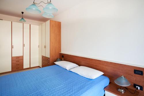 a bedroom with a blue bed with two pillows at APPARTAMENTO MARCONI B2 in Lido di Jesolo