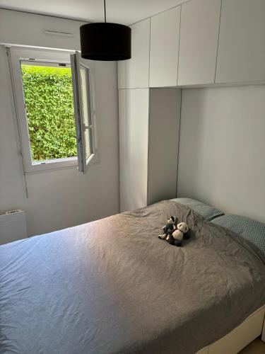 - un ours en peluche assis sur un lit dans une chambre dans l'établissement Havre de paix à Houlgate, à Houlgate