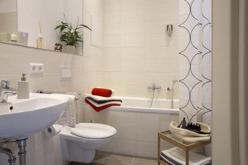 a bathroom with a sink and a toilet and a tub at Leon Suite Apartments in Leipzig