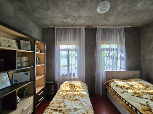 a bedroom with a bed and two windows at Maikostan in Shuakhevi