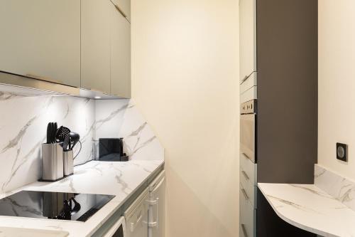 - une cuisine avec des comptoirs en marbre blanc et un évier dans l'établissement Pick A Flat's Apartments in Saint Louis - Quai des Orfèvres, à Paris