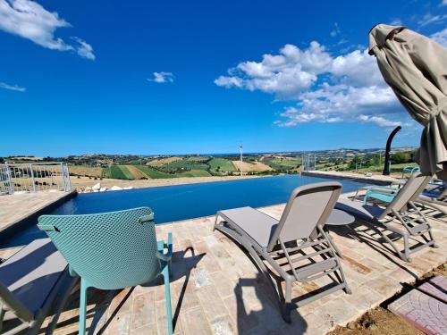 a patio with chairs and an umbrella and a pool at Stelle Girasoli e Conchiglie in Roncitelli