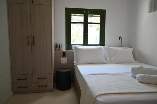 een witte slaapkamer met twee bedden en een raam bij Kythnos Seaside House Flampouria in Kithnos