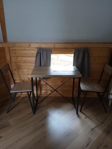 une table en bois et deux chaises assises à côté d'une fenêtre dans l'établissement Gite insolite kota finlandais, à Yzengremer