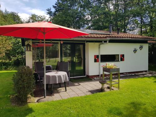 a patio with a table and a red umbrella at MemHill in Exloo