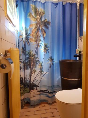 a bathroom with a blue shower curtain with palm trees at MemHill in Exloo