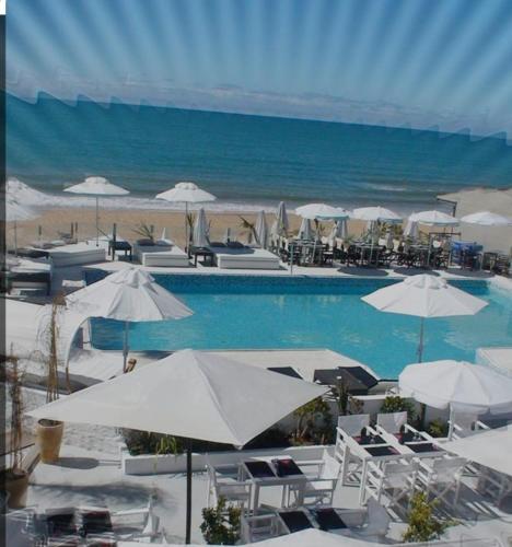 a swimming pool with white umbrellas and the beach at Hébergement bord de mer in Casablanca