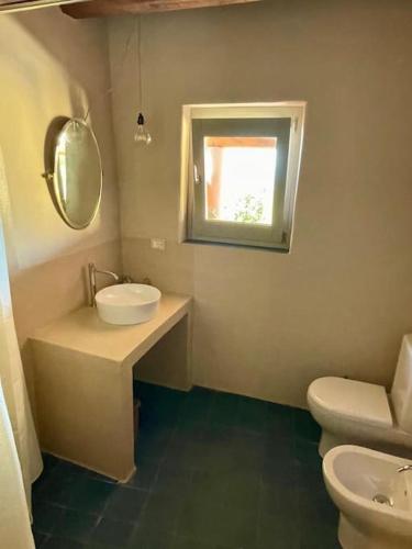 un bagno con lavandino, water e finestra di Casa Nica, giardino e vista mare a Malfa
