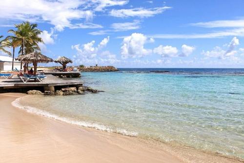 a beach with chairs and umbrellas and the ocean at La vida krys in Saint-François