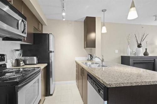 a kitchen with a sink and a stove top oven at Modern spacious Apt plus Solarium and Den in Downtown Vancouver with Parking and Pool in Vancouver