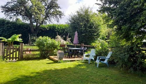 a garden with a table and an umbrella and chairs at La Maison du Haut Plessix in Clayes