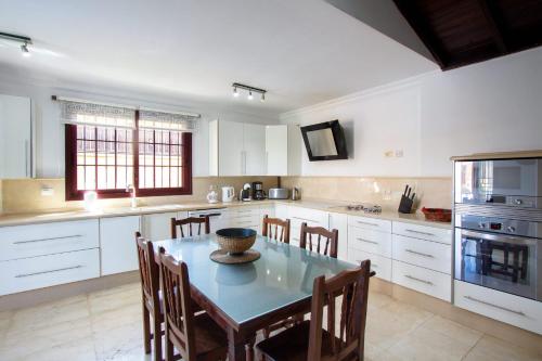 a kitchen with a table and chairs and a kitchen with white cabinets at Villa Jardín de Buda in Arona