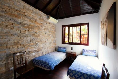 a room with two beds and a brick wall at Villa Jardín de Buda in Arona