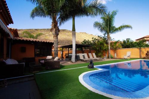 a backyard with a swimming pool and palm trees at Villa Jardín de Buda in Arona
