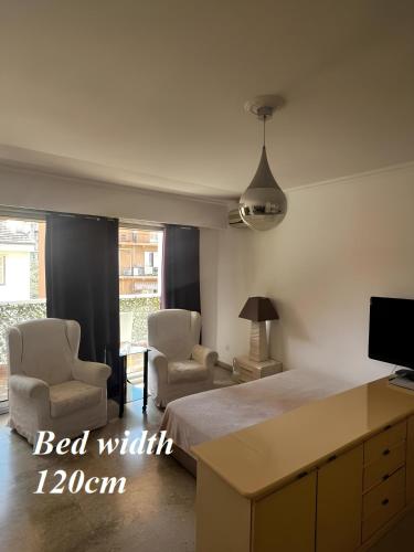 a bedroom with a bed with two chairs and a tv at Large Studio 907 near Monte Carlo Casino Monaco in Monte Carlo