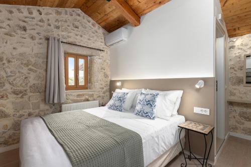 a bedroom with a bed and a stone wall at The Olive Mill Loft - Oil Mill to Lavish Leisure in Prinés