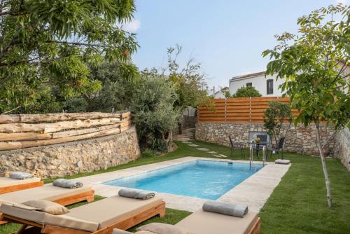 a swimming pool in a yard with two loungers and a stone wall at The Olive Mill Loft - Oil Mill to Lavish Leisure in Prinés