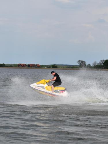 a man riding a jet ski on the water at Domki przy plaży in Ryn