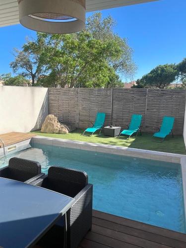 une piscine avec des chaises, une table et une clôture dans l'établissement Villa design Cap dAgde piscine et plage, au Grau-dʼAgde