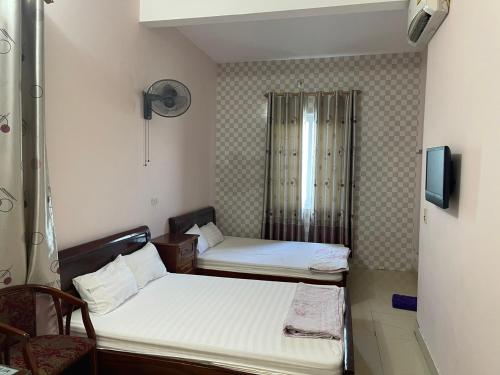 a small room with two beds and a tv at Nhà Nghỉ Long Lưu in Vinh