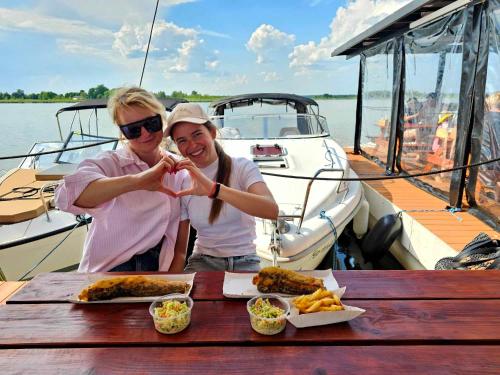 a man and woman sitting at a table with food on a boat at Domki przy plaży in Ryn
