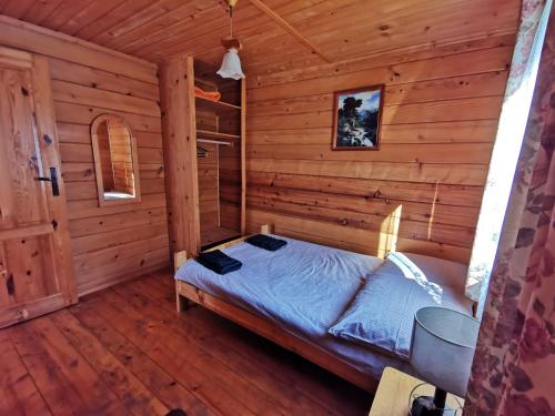 a bedroom with a bed in a log cabin at Domki Jaśmin 781-012-181 in Polańczyk