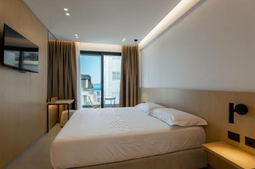 a bedroom with a white bed and a large window at Austin Boutique Hotel in Sarandë