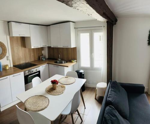 une cuisine et une salle à manger avec une table et des chaises blanches dans l'établissement Agréable T3 proche de Paris, à Saint-Brice-sous-Forêt