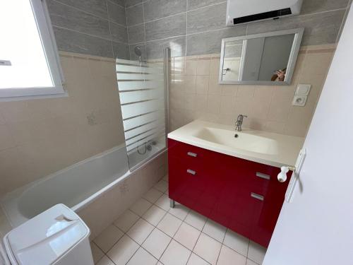La salle de bains est pourvue d'un lavabo et d'une armoire rouge. dans l'établissement LA TRANCHE SUR MER centre ville emplacement voiture, à La Tranche-sur-Mer