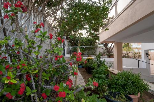 a garden with red flowers and plants on a balcony at Unbeatable View, Family apartment in Rafina